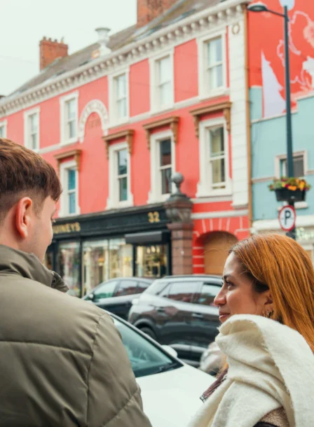 Couple enjoying a stroll near colourful buildings and shops in Dundalk town centre.