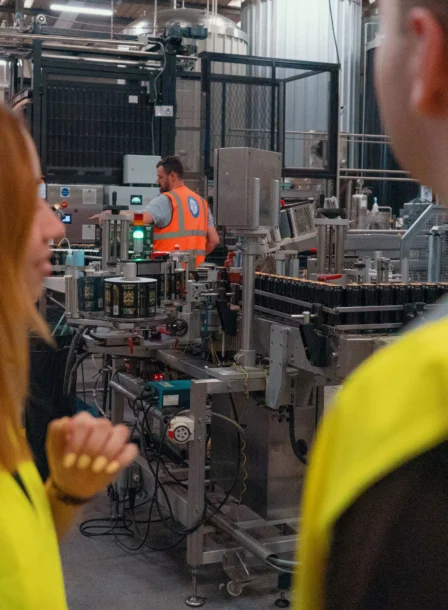 A couple in high vis jackets look at machinery during at a distillery tour