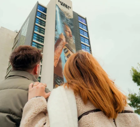 A couple admires The Gateway Hotel Dundalk from outside; large mural visible on building.