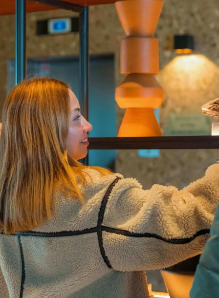 A couple enjoys browsing books in The Gateway Hotel lobby's cosy, warmly-lit setting.