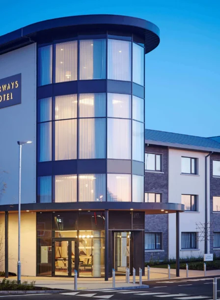 Modern entrance of The Gateway Hotel Dundalk at dusk, warmly lit, with visible hotel sign.