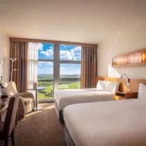 Bright hotel room at The Gateway Hotel Dundalk, featuring two large beds and countryside views.