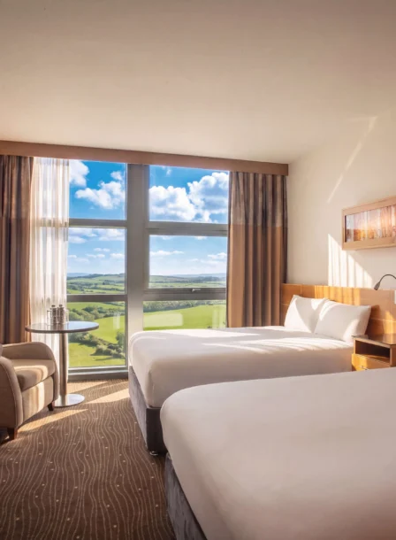 Bright hotel room at The Gateway Hotel Dundalk, featuring two large beds and countryside views.