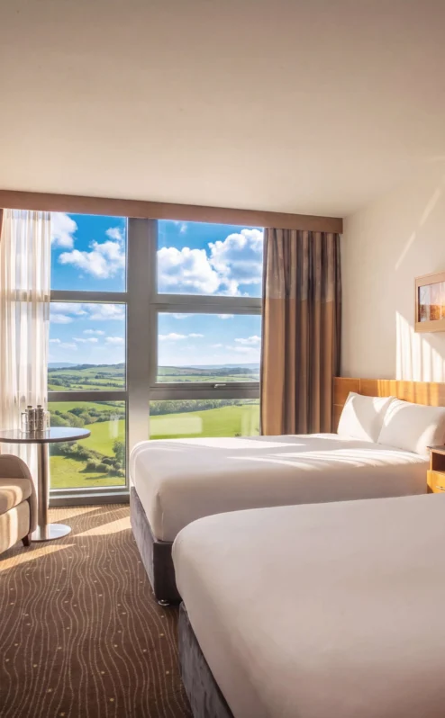 Bright hotel room at The Gateway Hotel Dundalk, featuring two large beds and countryside views.