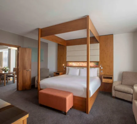 Modern hotel room with a large bed, comfortable seating, and warm, inviting decor.