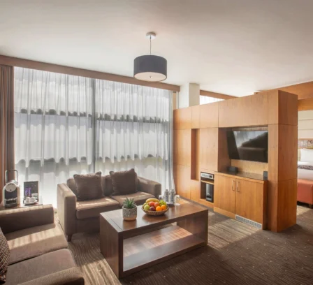 Spacious hotel suite with modern decor, cosy seating, and large windows at The Gateway Hotel.