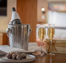Luxurious hotel room with wine, chocolates, and a gift box, creating a romantic setting.