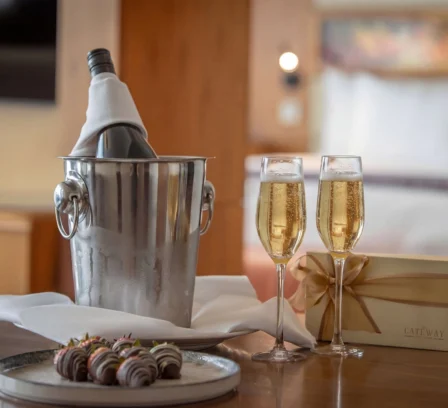 Luxurious hotel room with wine, chocolates, and a gift box, creating a romantic setting.