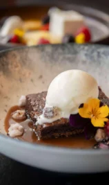 Dessert with ice cream and berries at The Gateway Hotel with family dining setting.