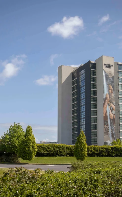 A family enjoys sunny outdoors near The Gateway Hotel Dundalk with lush greenery around.