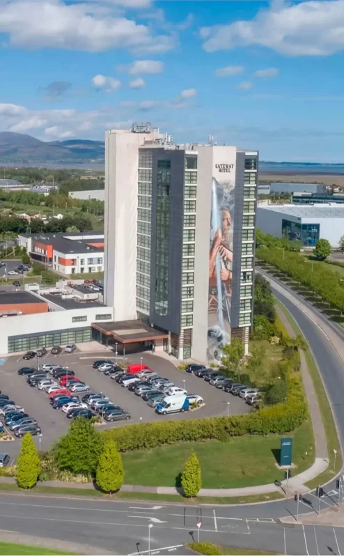 Aerial view of The Gateway Hotel Dundalk with parked cars and lush green surroundings.