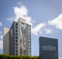 A tall hotel building under a clear blue sky with The Gateway Hotel Dundalk sign in front.
