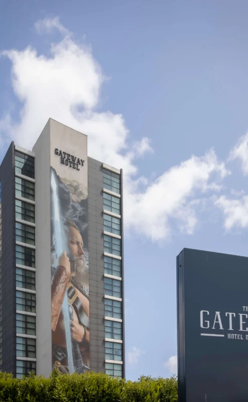 A tall hotel building under a clear blue sky with The Gateway Hotel Dundalk sign in front.