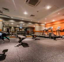 A modern gym at The Gateway Hotel with exercise equipment and warm lighting.