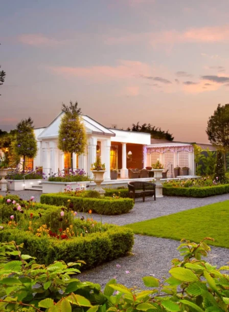 A family enjoys a stroll through lush gardens outside The Gateway Hotel at sunset.