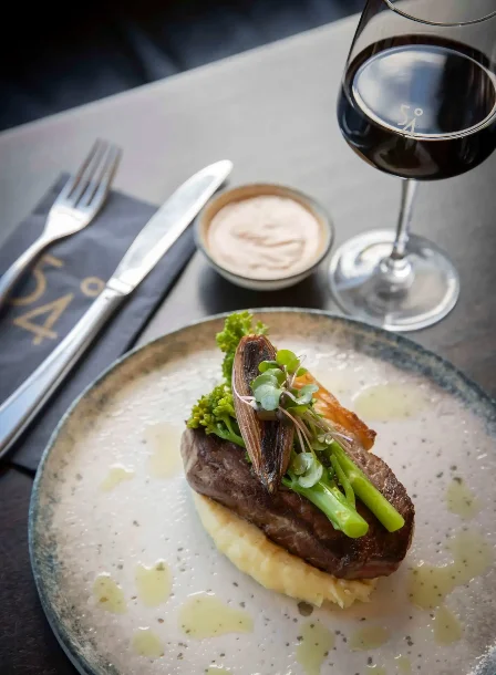 Gourmet steak dish with vegetables, glass of red wine at The Gateway Hotel restaurant.