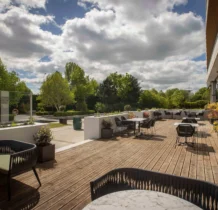 Family enjoying sunny day on hotel terrace with lush greenery and modern decor.