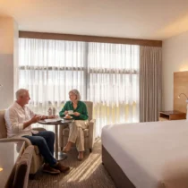 Elderly couple enjoying tea in a modern, warmly-lit hotel room at The Gateway Hotel Dundalk.