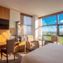 Modern hotel room with scenic countryside view, cosy seating, and inviting natural light.