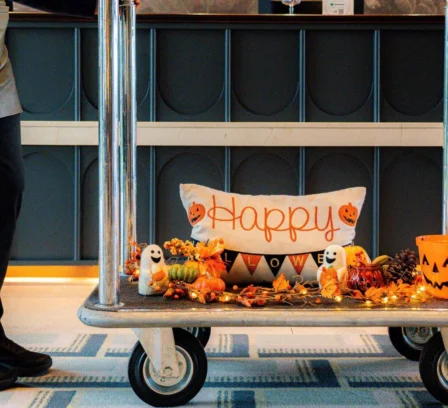 Hotel bell cart with autumn Halloween decorations and a family checking in warmly