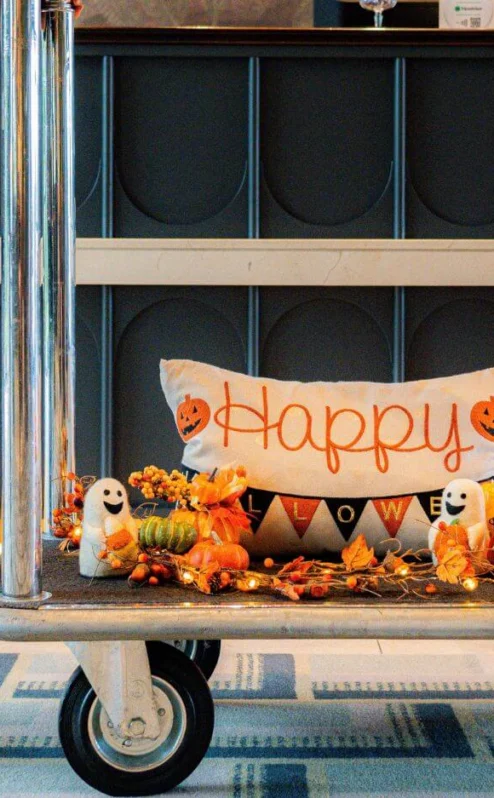 Hotel bell cart with autumn Halloween decorations and a family checking in warmly